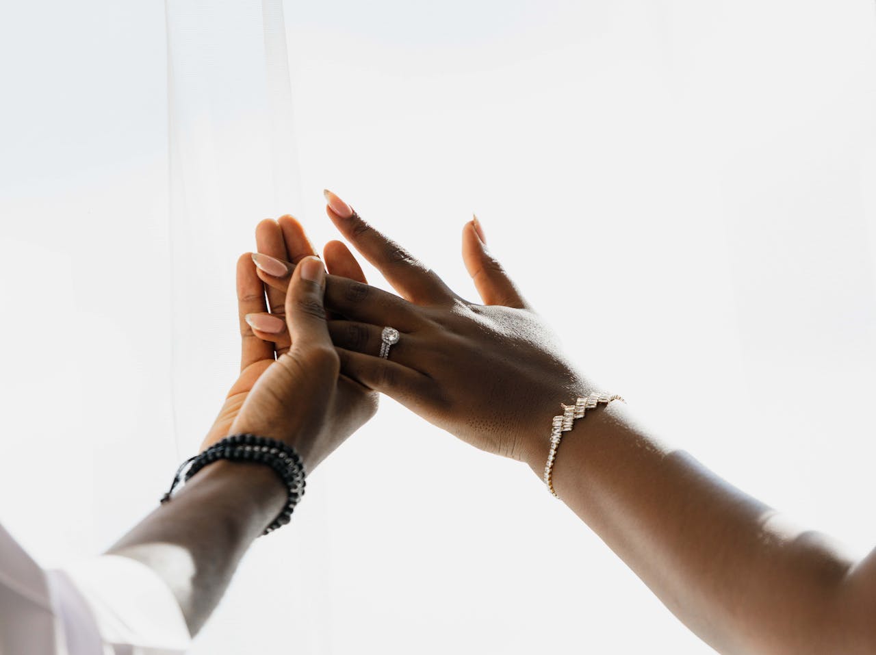 Close-up of hands with elegant wedding rings and jewelry, signifying love and unity.
